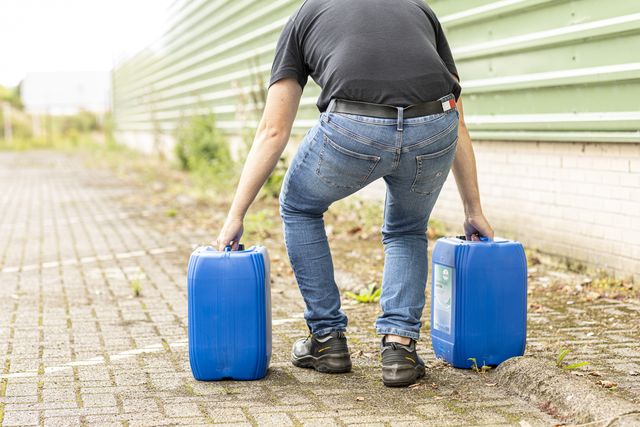 Medewerker tilt twee jerrycans, een voorbeeld van fysieke belasting