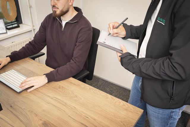 Adviseur van Prevensa in gesprek met een medewerker aan zijn werkplek